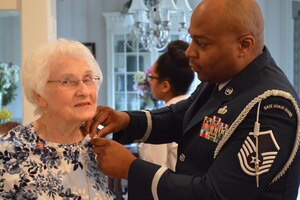 U.S. Air Force Master Sgt. Elroy Williams, 633rd Force Support Squadron Self-Assessment program manager, pins the wife of a veteran during an Armed Forces Day pinning ceremony at a hospice in Williamsburg, Va., May 16, 2015. The event was done in honor of veterans and families of veterans who have served in the military in support of our nation. (Courtesy Photo) 