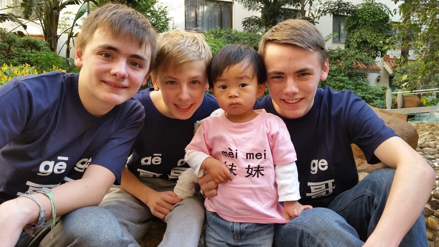 From left to right, Ivan, 13, Thaddeus, 14, and Sawyer Krueger, 17, huddle together with their newly adopted little sister Susan in Guangzhou, Guangdong Province, China, Dec. 22, 2014. The Krueger family traveled to China to pick up their Waiting Child, a process that took nearly two years. The boys' shirts read "big brother" and Susan's shirt says "little sister."  (courtesy photo)