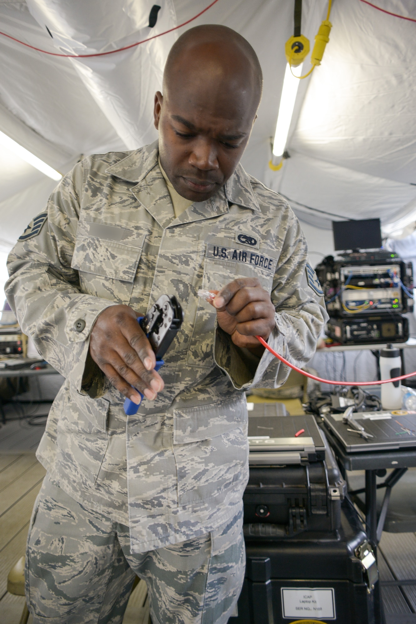 A cyber transport journeyman with the 283rd Combat Communications Squadron (CCS) from Dobbins Air Reserve Base, Georgia Air National Guard, installs an RJ-45 head on a Cat-5 cable for a Theater Deployable Communications System during the Sentry Savannah 15-2 exercise at The Air Dominance Center, Savannah, Ga., May 8, 2015. Sentry Savannah is a National Guard Bureau sponsored training event with a focus on Joint Dissimilar Air Combat Training and 5th Generation Fighter Integration. It offers a chance for fighter pilots to participate in war simulations that depict what they would face in real-world scenarios. During the exercise the 283rd CBCS provided NIPR, SIPR, and voice services to the 117th Air Control Squadron Air Battle Element and extended service to their deployed radar site. Working together the two units provided vital data to help the fighter pilots complete their missions. (U.S. Air National Guard photo by the 116th Air Control Wing Public Affairs/Released) (Name of military member has been blurred and withheld for security purposes)