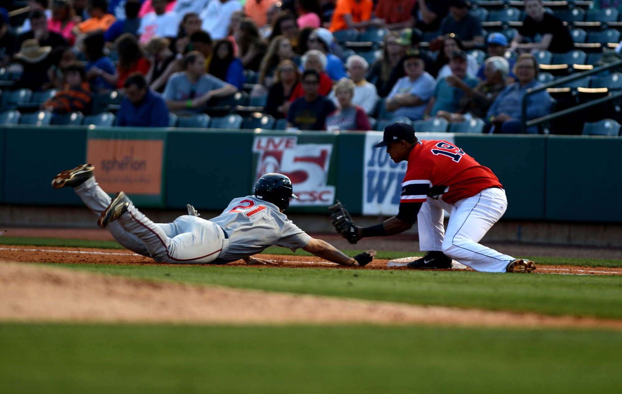 A baseball player dives into first base during a military appreciation baseball game held at the Joseph P. Riley Jr. Ballpark in Charleston, S.C., May 14, 2015. Throughout the game, several appreciation events were held for military members and their families including tug-o-war, water races, and throwing the last pitch. (U.S. Air Force photo by Senior Airman Jensen Stidham/Released)