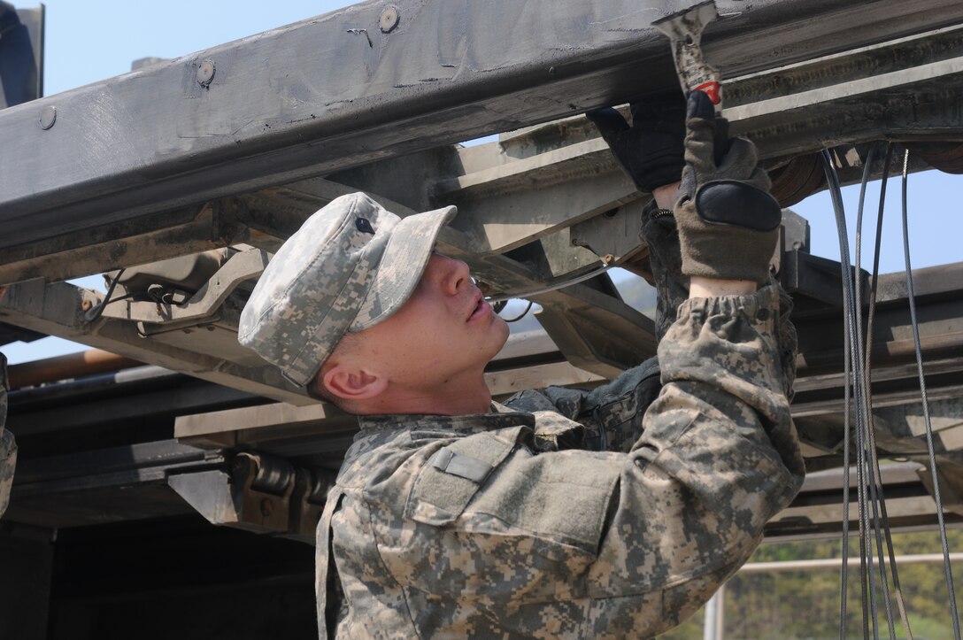 Army Spc. Steven Koroza, a multiple launch rocket system crew member and gunner assigned to the 2nd Infantry Division’s Bravo Battery, 1st Battalion, 38th Field Artillery Regiment, 210th Field Artillery Brigade, applies grease to a rocket holder April 27, 2015, while conducting preventive maintenance checks and services at the battalion motor pool on Camp Casey, South Korea. Courtesy Photo
