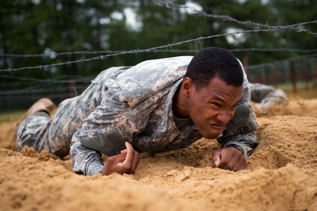 A paratrooper crawls under the barbed wire obstacle part of the team assault course competition during All-American Week on Fort Bragg, N.C. May 19, 2015.