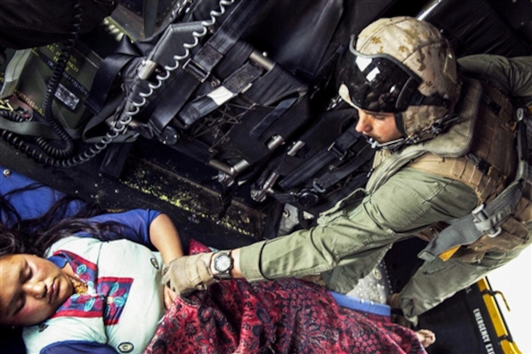 U.S. Marine Cpl. Brian Schmidt helps an earthquake victim on a UH-1Y Huey helicopter while transporting her to safety during Operation Sahayogi Haat, May 19, 2015. 