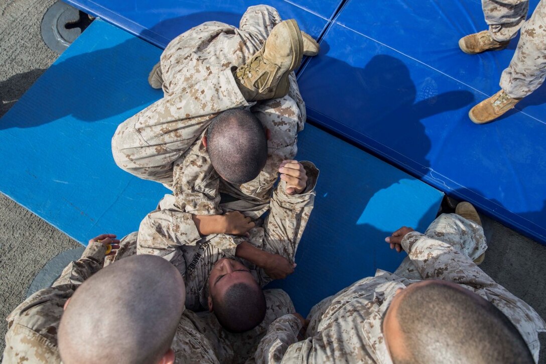U.S. Marine Pfc. Andres Bravo, top, pratices ground fighting techniques with Lance Cpl. Jaime Camacho during Marine Corps Martial Arts Program training aboard the USS Rushmore (LSD 47) at sea in the Pacific Ocean, May 13, 2015. Bravo is a rifleman and Camacho is an automatic rifleman with Kilo Company, Battalion Landing Team 3rd Battalion, 1st Marine Regiment, 15th Marine Expeditionary Unit. MCMAP training helps the Marines maintain a warrior mindset while deployed aboard the ships fo the Essex Amphibious Ready Group. (U.S. Marine Corps photo by Sgt. Emmanuel Ramos/Released)