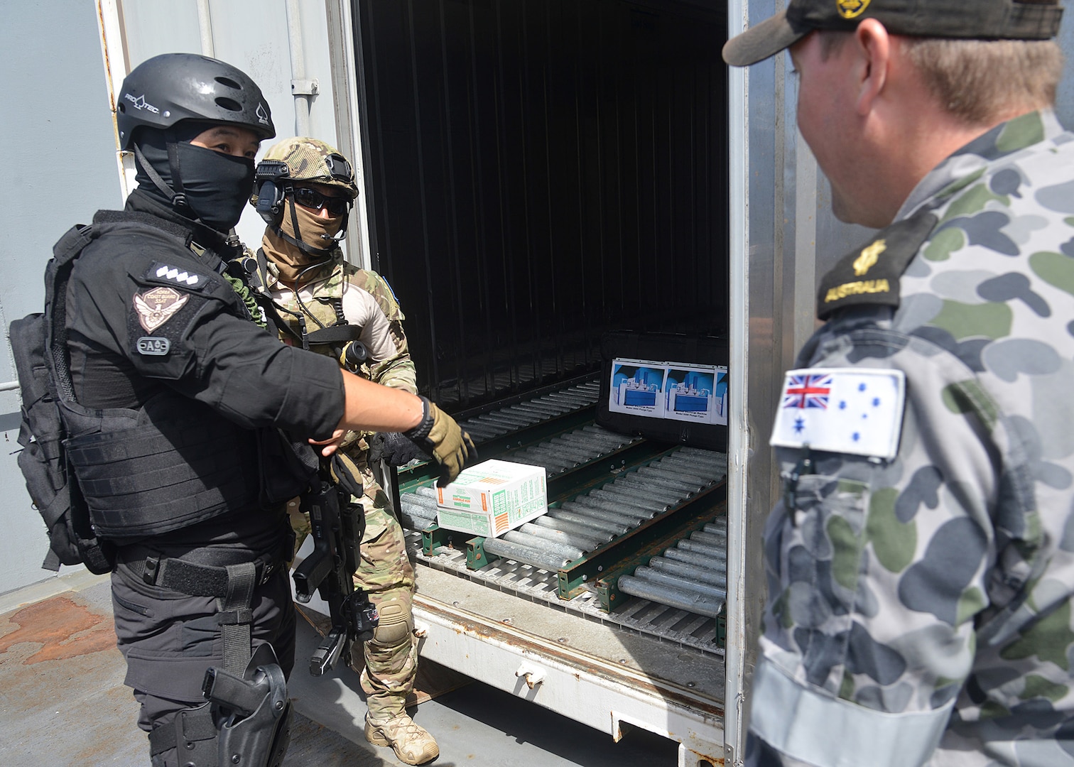 PACIFIC OCEAN (Aug. 6, 2014) A Republic of Korea (ROK) Coastguard and a ROK Navy Sailor question Able Seaman Grahame Kelaher about a mock electronic discharge machine they found in a conex container on USNS Henry J. Kaiser (T-AO 187) during a live exercise for Fortune Guard 2014. Fortune Guard is the region’s premier exercise designed to build regional weapons of mass destruction counter-proliferation capacity and long-term commitment to the proliferation security initiative in the Indo-Asia-Pacific. (U.S. Navy photo by Mass Communication Specialist 1st class Amanda Dunford/Released).