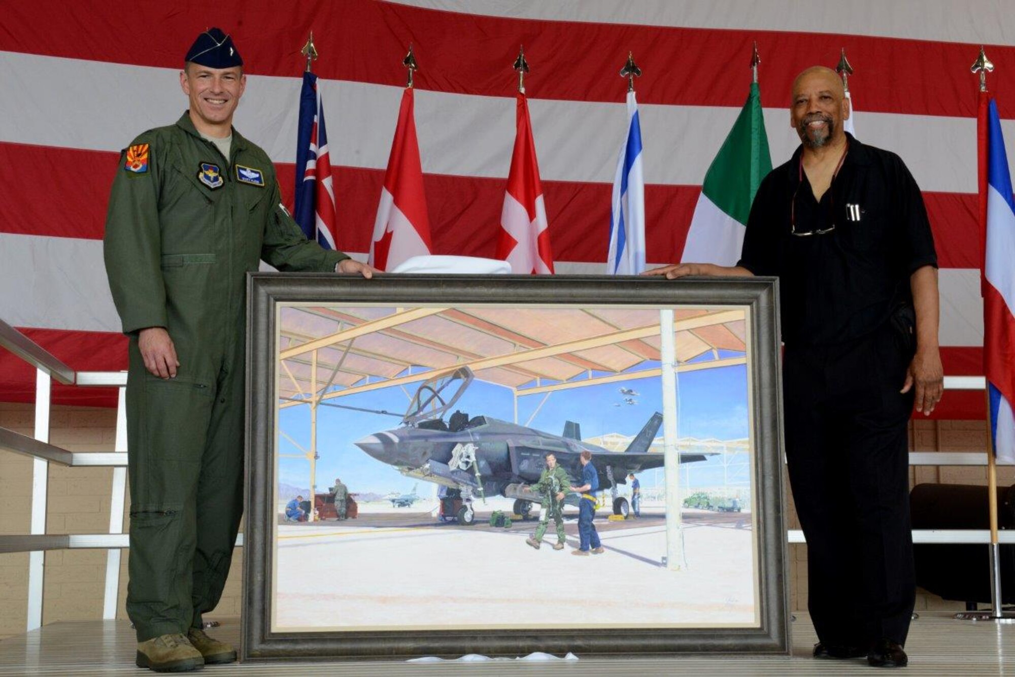 Brig. Gen. Scott Pleus, 56th Fighter Wing commander, and Charles Lilly, lithograph artist, unveil the new Fighter wing lithograph May 21, 2015, at Luke Air Force Base, Arizona. The presentation took place during the 56th Fighter Wing change of mission ceremony. (U.S. Air Force photo by Airman Pedro Mota)