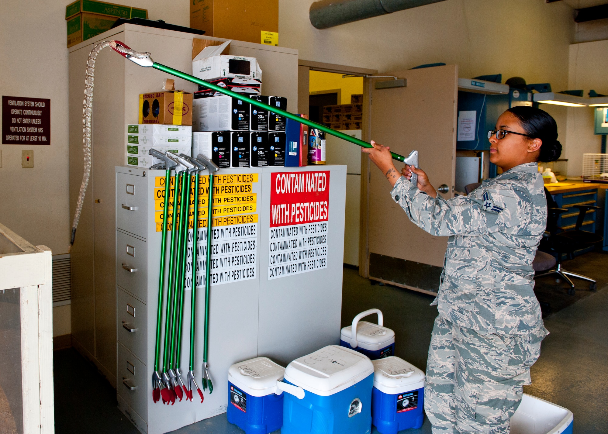 Airman 1st Class Taylor Bradford, 49th Civil Engineer Squadron pest management apprentice safely removes a Blacktail Rattlesnake from its tank in their facility at Holloman Air Force Base, N.M., May 14, 2015.  Pest Management is a small shop of one civilian and three active duty members who handle all pest control issues on Holloman. From ants, spiders, coyotes, raccoons, rattlesnakes, and mosquitos, pest control knows how to keep our base and our ecosystems safe and in-line. (U.S. Air Force photo by Senior Airman Leah Ferrante/released)