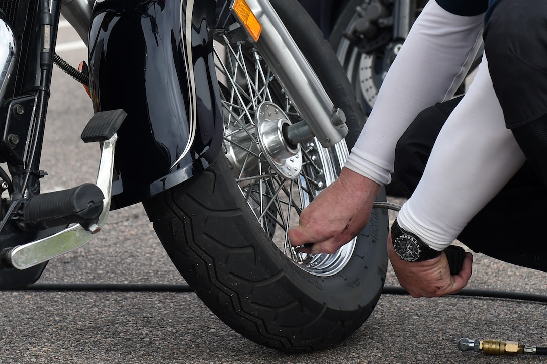 Rodger Scott, 460th Space Communications Squadron deputy, puts air into the tires of a Team Buckley member’s motorcycle before their safety ride May 15, 2015, on Buckley Air Force Base, Colo. The 460th SCS had this motorcycle ride to give “on-the-job” training to ensure young members of the squadron know how to ride safely. (U.S. Air Force photo by Airman 1st Class Emily E. Amyotte/Released)