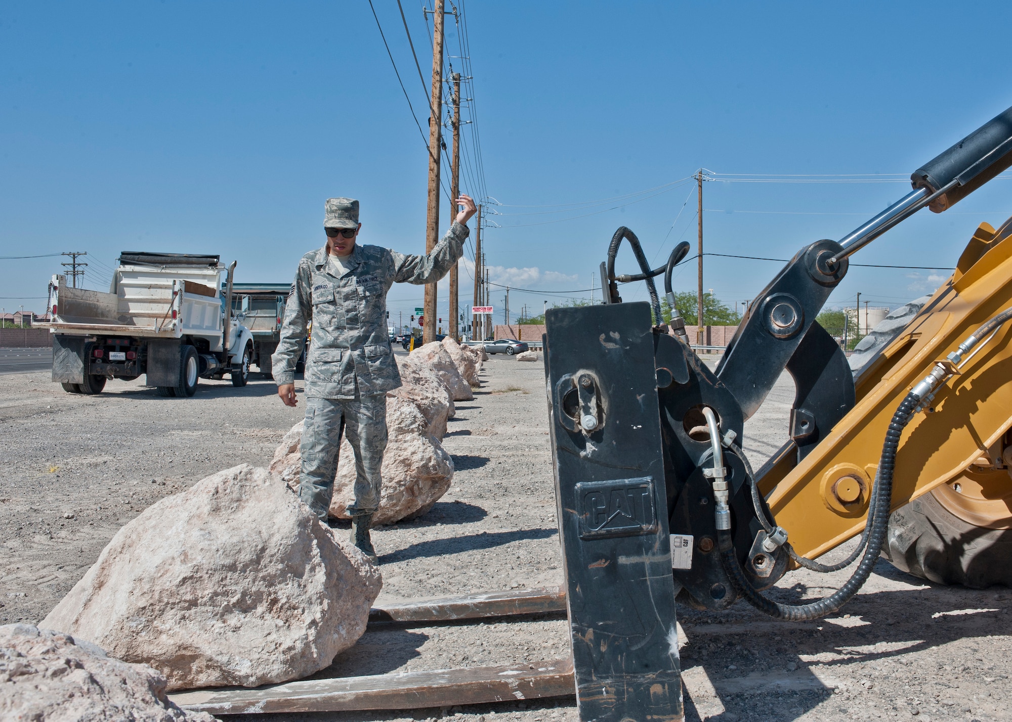 Staff Sgt. Josiah Santiago, 99th Civil Engineer Squadron heavy equipment journeyman, calls in a fork lift to lift and place a boulder into position as part of a “Dirt Boyz” project at Nellis Air Force Base, Nev., May 19. Dirt Boyz are in charge of all heavy equipment on base which include dump trucks, fork lifts, loaders, excavators, bulldozers, bobcats, graders and cranes. (U.S. Air Force photo by Airman 1st Class Jake Carter)