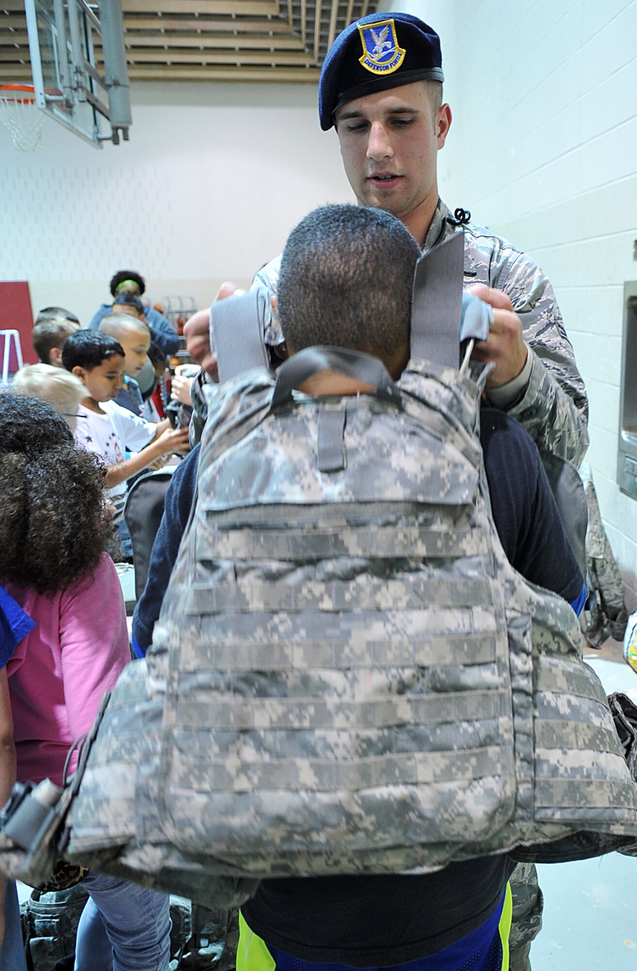 U.S. Air Force Airman 1st Class Richard Antony II places a Kevlar vest on a child at the youth center May 15 as part of Police Week.  Police week was established in 1962 by President John F. Kennedy to honor fallen officers. (U.S. Air Force photo by Charles Haymond)