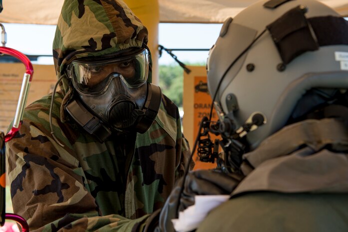 U.S. Air Force Airman 1st Class Michael Gibbs-Forde, an aircrew flight equipment journeyman with the 437th Operations Support Squadron, assists Airman 1st Class Matthew Link, a C-17 loadmaster with the 16th Airlift Squadron, at a Crescent Reach 15 decontamination station May 20, 2015, at Joint Base Charleston, S.C. This local exercise, which tested and evaluated Joint Base Charleston's ability to launch a large aircraft formation in addition to process and deploy duty passengers and cargo in response to a simulated crisis abroad from May 18-21. Deploying members' ability to survive and operate in deployed environments was also exercise through Chemical, Biological, Radiological, Nuclear Explosives training and evaluation events. (U.S. Air Force photo by Staff Sgt. Jamal D. Sutter)