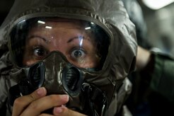 Senior Airman Amanda Fields, a C-17 loadmaster with the 17th Airlift Squadron, widens her eyes as a co-worker secures her mission-oriented protective posture gear May 20, 2015, during Crescent Reach 2015 at Joint Base Charleston, S.C. This local exercise, which tested and evaluated Joint Base Charleston's ability to launch a large aircraft formation in addition to processing and deploying duty passengers and cargo in response to a simulated crisis abroad May 18 - 21, 2015. Deploying members' ability to survive and operate in deployed environments was also exercise through Chemical, Biological, Radiological, Nuclear Explosives training and evaluation events. (U.S. Air Force photo by Staff Sgt. Jamal D. Sutter) 

