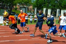 Air Force District of Washington Command Chief Master Sgt. Ferrell Thomas hands the baton to athlete Gustavo Majano while running the 400 meter relay in the Special Olympics D.C. Summer Games at The Catholic University of America in Washington D.C., May 20, 2015. The Summer Games is one of the largest Special Olympics District of Columbia events. (U.S. Air Force photo/Michael Martin)