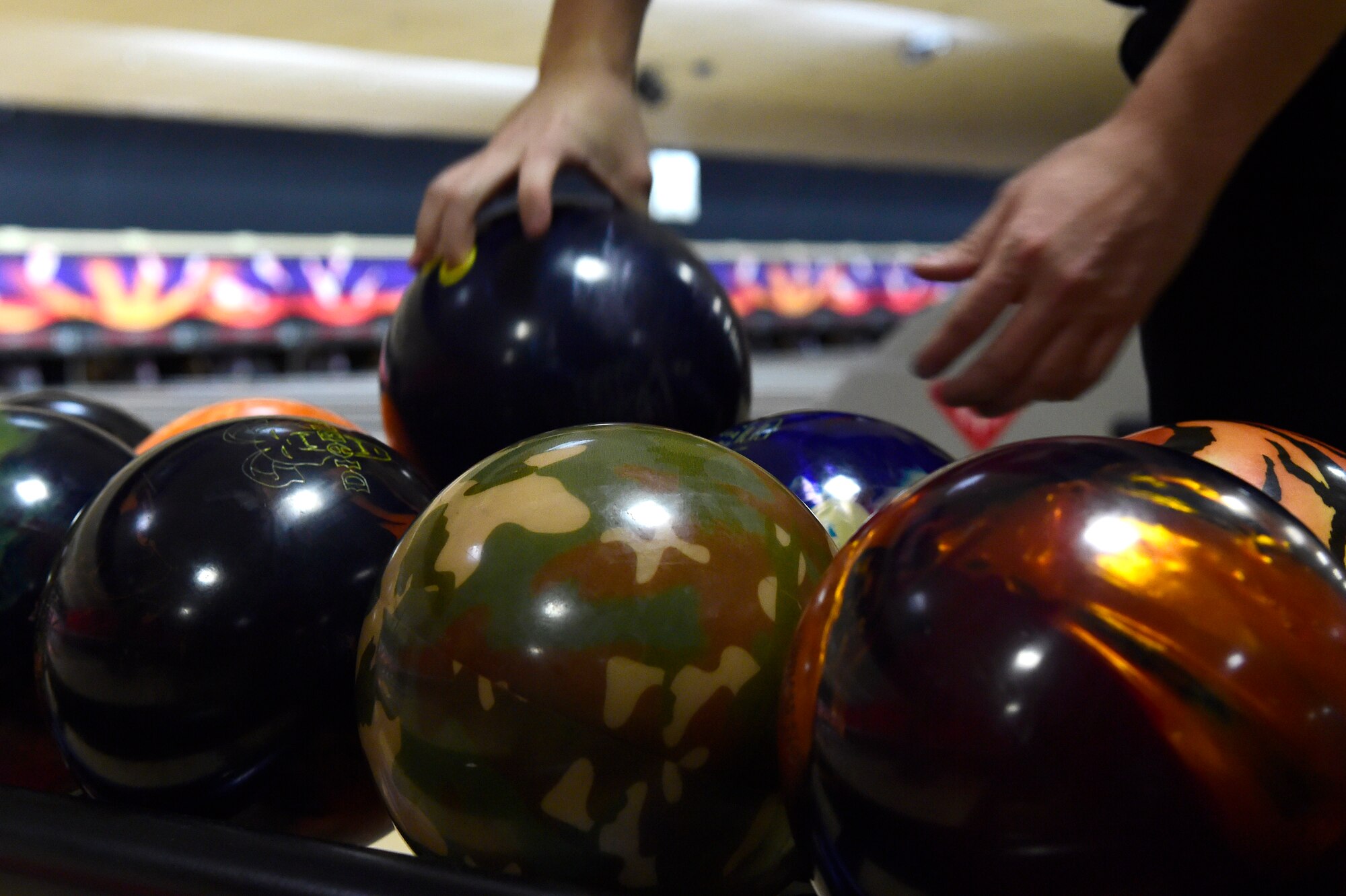 A bowler chooses a bowling ball during the Tri-Wing Sports Day competition May 20, 2015, on Buckley Air Force Base, Colo. Tri-Wing Sports Day is held once a year between the three Air Force Space Command bases and is intended to promote healthy, active lifestyles and friendly competition. The bases competed against each other in over 15 sports such as volleyball, football, tennis and softball among others. (U.S. Air Force photo by Staff Sgt. Stephany Richards/Released)