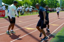 Athlete Marlon Bryant reaches forward to hand the baton to Air Force District of Washington Command Chief Master Sgt. Ferrell Thomas during the 400 meter relay at the Special Olympics D.C. Summer Games at The Catholic University of America in Washington D.C., May 20, 2015.  The mission of Special Olympics is to provide year-round sports training and athletic competition in a variety of Olympic-type sports for children and adults with intellectual disabilities, giving them continuing opportunities to develop physical fitness, demonstrate courage, experience joy and participate in a sharing of gifts, skills and friendship with their families, other Special Olympics athletes and the community. (U.S. Air Force photo/Michael Martin)