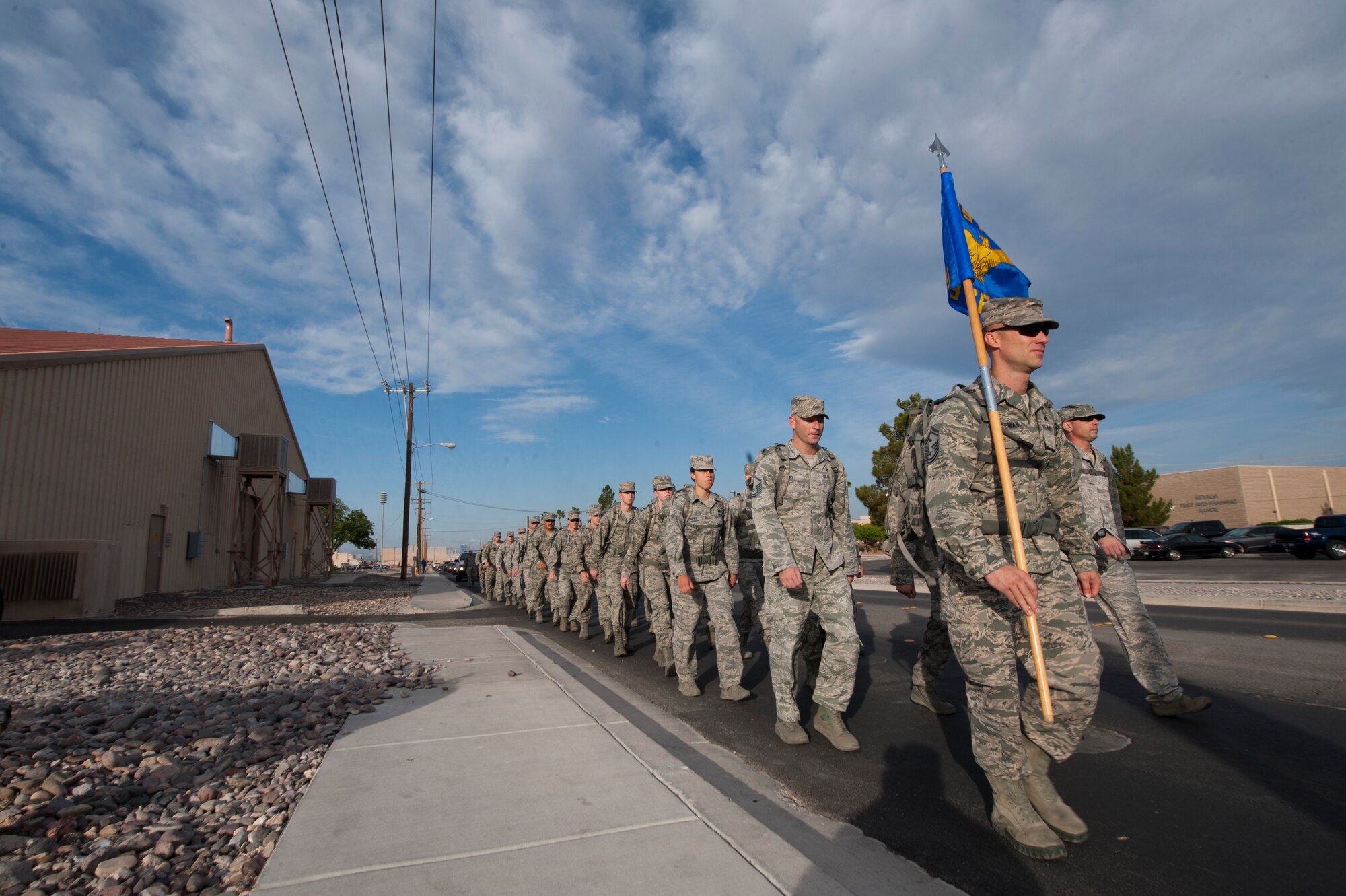 Airmen assigned to the 99th Security Forces Squadron march down the road halfway through the National Police Week 10K memorial ruck march at Nellis Air Force Base, Nev., May 13, 2015. Throughout the march, the formation stopped at various hydration stations and rendered honors to fallen security forces Airmen. (U.S. Air Force photo by Senior Airman Joshua Kleinholz)