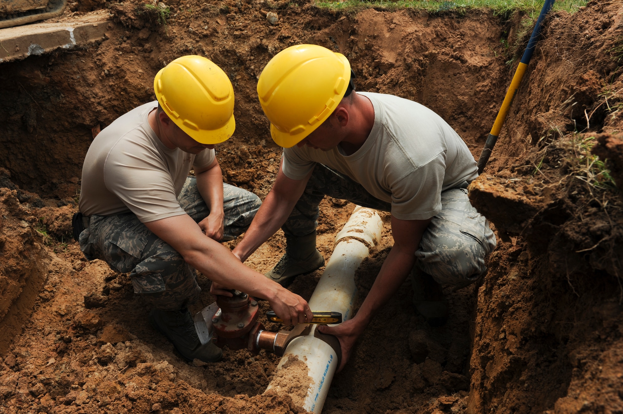 Senior Airman Matthew Davis, 19th Civil Engineer Squadron water and fuel system journeyman, and Staff Sgt. Scott Triplett, 19th Civil Engineer Squadron water and fuel system craftsman, secure a saddle tee on a waterline during recent upgrades May 7, 2015, at Little Rock Air Force Base, Ark. The saddle tee allows the Airmen to tap into a live waterline without having to shut down water access on base. (U.S. Air Force photo by Senior Airman Scott Poe)