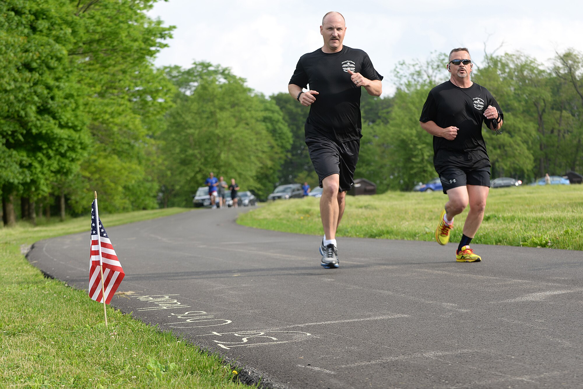 Team Scott members pass by flags with names of fallen Port Dawgs during the Port Dawgs Memorial Run 5k around Scott Lake May 15, 2015 at Scott Air Force Base, Illinois. Names were written along the path in honor of fallen Aerial Transporters or “Port Dawgs.” (U.S. Air Force photo/Senior Airman Joshua Eikren)