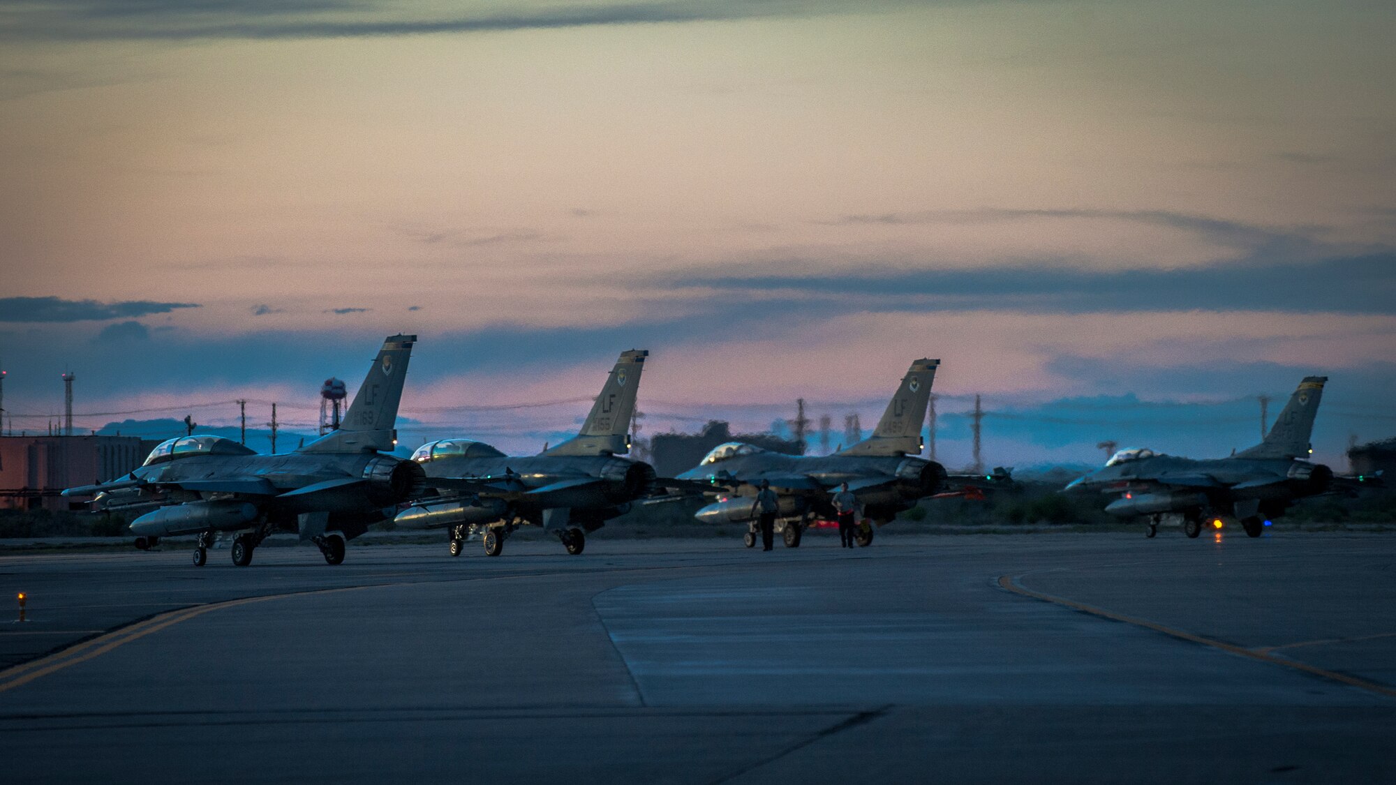 F-16 Fighting Falcons sit on the runway prior to departure at Holloman Air Force Base, N.M. May 13, 2015. The 311th Fighter Squadron, a tenant unit from Luke Air Force Base, Ariz., trains F-16 pilots at Holloman. The students are currently at a point in their syllabus where they are learning how to use night vision goggles and perform combat night operations.  (U.S. Air Force photo by Airman 1st Class Emily A. Kenney/Released)