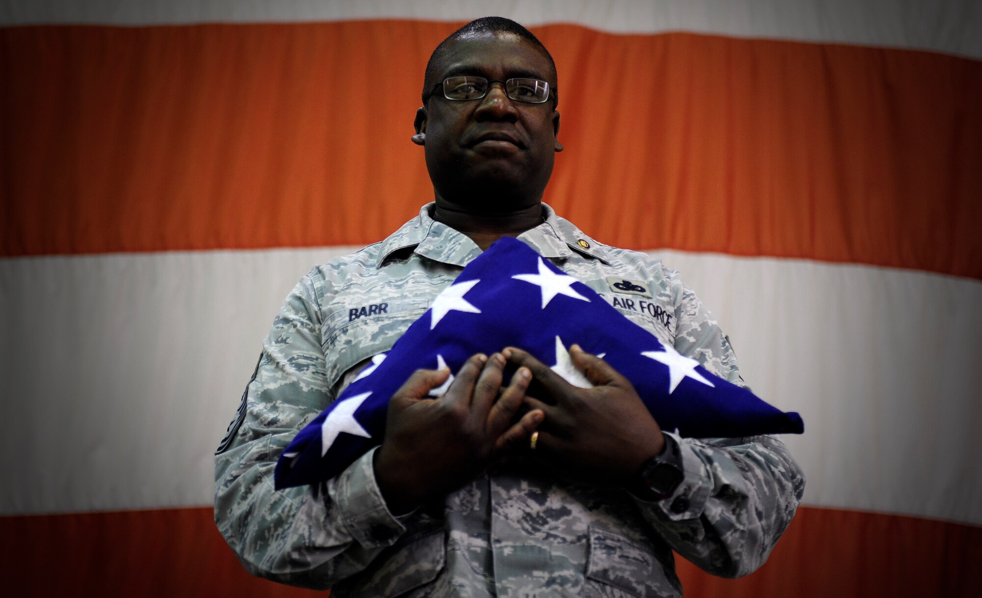 Chief Master Sgt. Lee Barr, 8th Fighter Wing command chief, holds an American flag folded by the 8th FW honor guard as part of his retirement ceremony at Kunsan Air Base, Republic of Korea, May 12, 2015. Barr spent 22 years in the security forces career field while supporting and deploying in Operations Desert Shield and Storm, Southern Watch, Noble Eagle, Iraqi Freedom and Odyssey Dawn. He will have served in the Air Force for 30 years when he retires in November. (U.S. Air Force photo by Senior Airman Taylor Curry/Released)