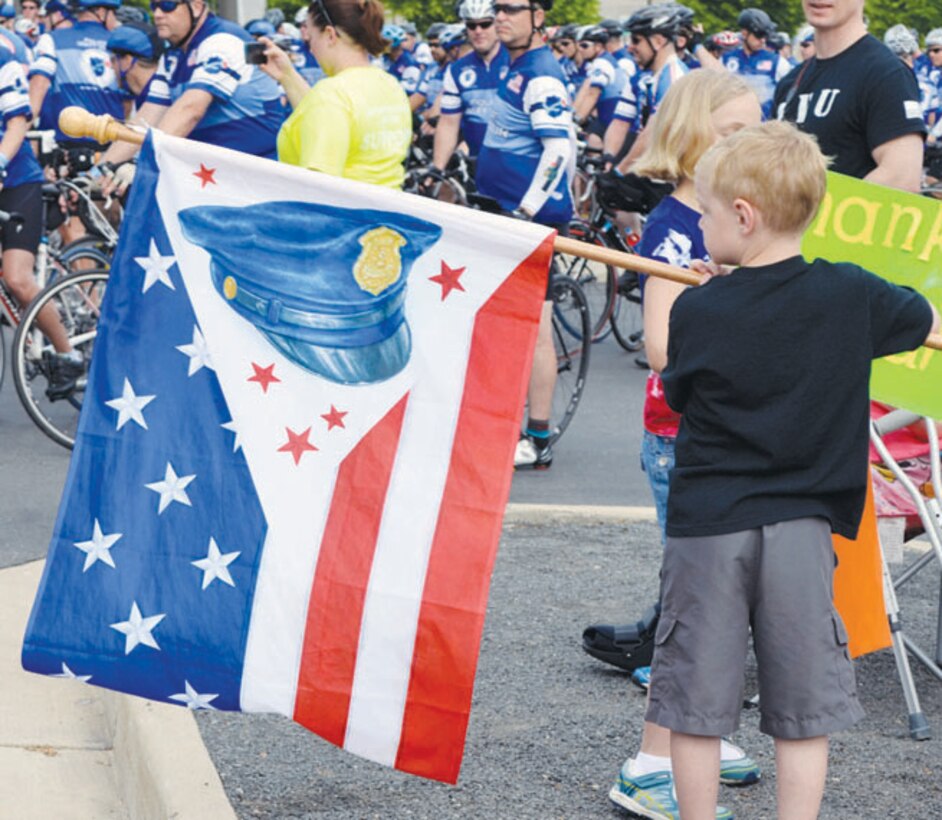 A young boy waves a police flag in support of the bicycle riders gathered at the National Museum of the Marine Corps for the final leg of the Policy Unity Tour and the Law Enforcement United Road to Hope bicycle rides on May 12.