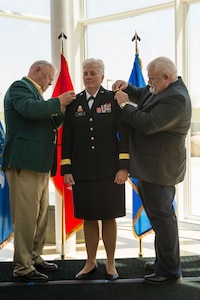 Former North Dakota adjutant general, retired Maj. Gen. Keith Bjerke, left, and Wilz’s brother, retired Army National Guard Col. Greg Wilz, affix brigadier general officer shoulder boards on Giselle “Gigi” Wilz during her promotion ceremony at the Heritage Center, in Bismarck, North Dakota on May 20, 2015. 