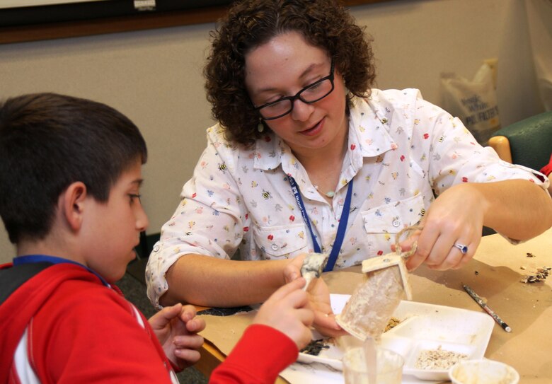Christine Renzoni assists a young participant decorate his bird feeder during the Take Your Daughters and Sons to Work STEM event April 30, 2015.