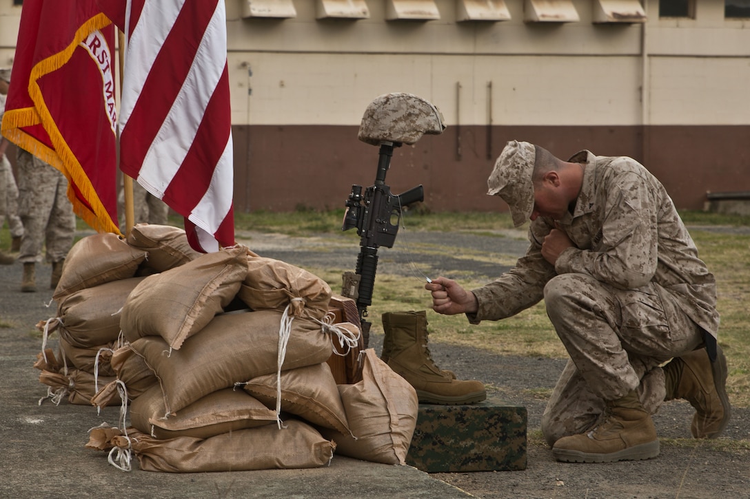 Lance Cpl. Matthew Whitfield, a machine gunner with Combat Logistics Battalion 15, pays respects to his fallen comrade by clutching his dog tags in his hand at Marine Corps Training Area Bellows, May 19, 2015. Whitfield gave his personal reflection in the ceremony as well. (U.S. Marine Corps photo by Cpl. Khalil Ross/Released)