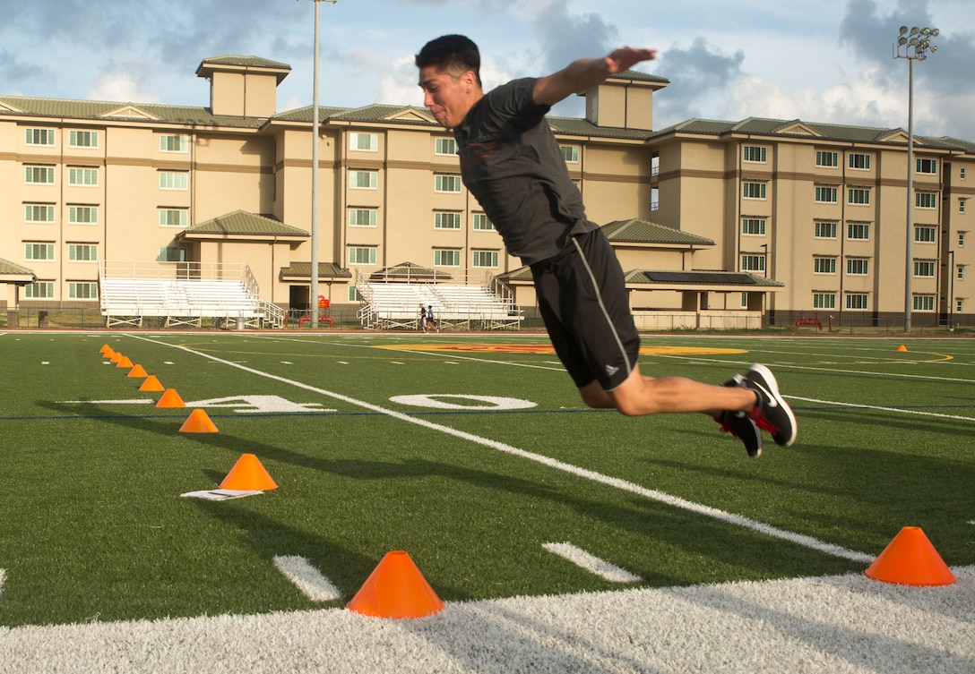 Petty Officer 3rd Class Lawrence Montoya, an aviation electronics technician with Marine Aviation Logistics Squadron 24, soars throught the air as he conducts a standing long jump for distance May 18, 2015, at Pop Warner Field. Lawrence attempted the jump three times and used the longest jump of the three as his assessment score. (U.S. Marine Corps photo by Cpl. Khalil Ross/Released)