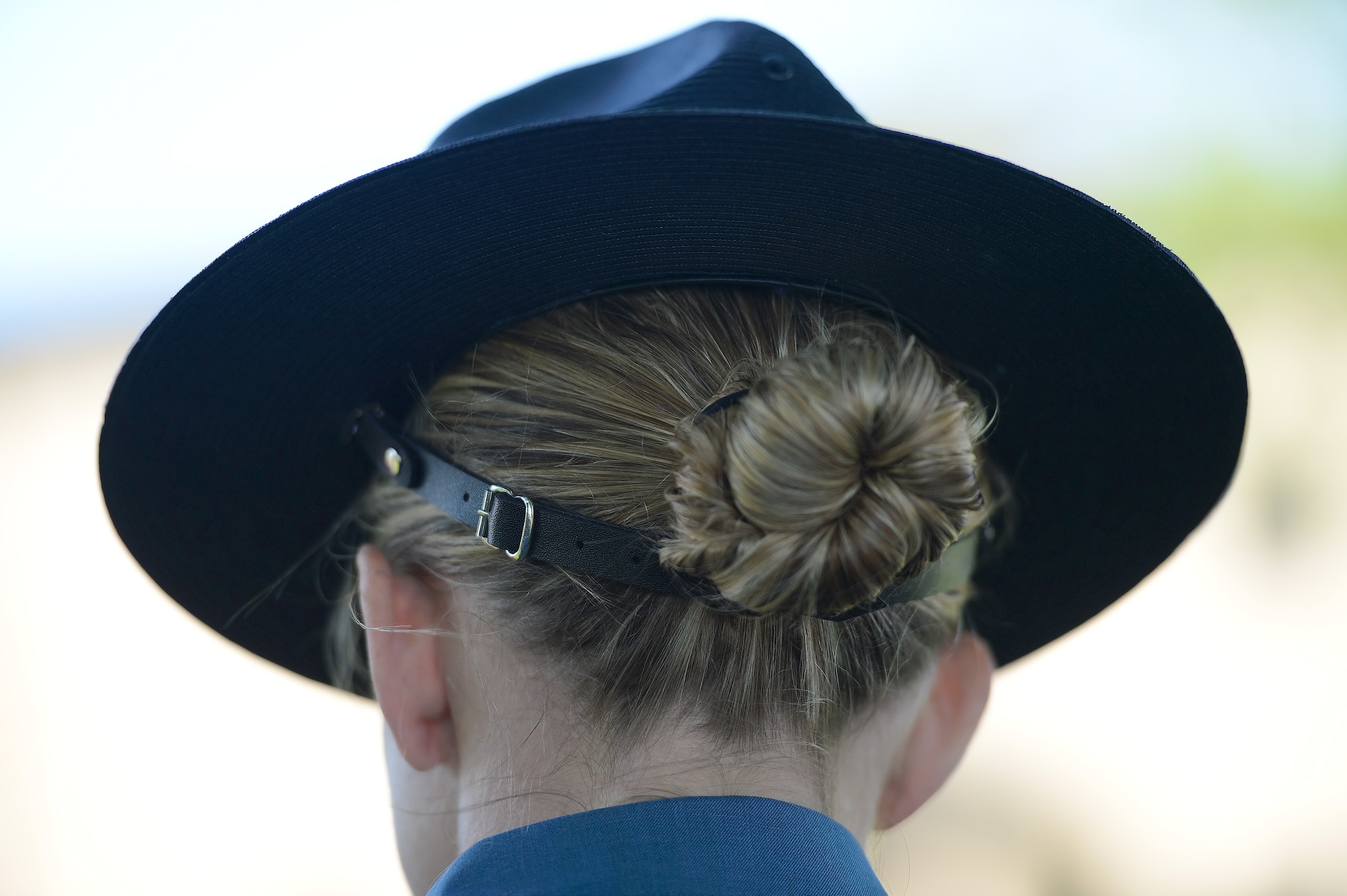 A campaign cap worn by Trooper Christine Armstrong, Delaware State Police, sits with a typical downward-tilt as she stands in formation with other law-enforcement representatives during the formal retreat ceremony marking the end of Police Week May 15, 2015, at Dover Air Force Base, Del. The hat is secured by a tight leather nape strap under her hair bun. Team Dover along with representatives from local and regional law enforcement agencies attended the formal retreat ceremony. (U.S. Air Force photo/Greg L. Davis)