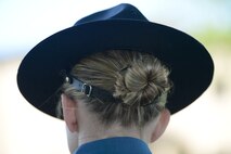 A campaign cap worn by Trooper Christine Armstrong, Delaware State Police, sits with a typical downward-tilt as she stands in formation with other law-enforcement representatives during the formal retreat ceremony marking the end of Police Week May 15, 2015, at Dover Air Force Base, Del. The hat is secured by a tight leather nape strap under her hair bun. Team Dover along with representatives from local and regional law enforcement agencies attended the formal retreat ceremony. (U.S. Air Force photo/Greg L. Davis)