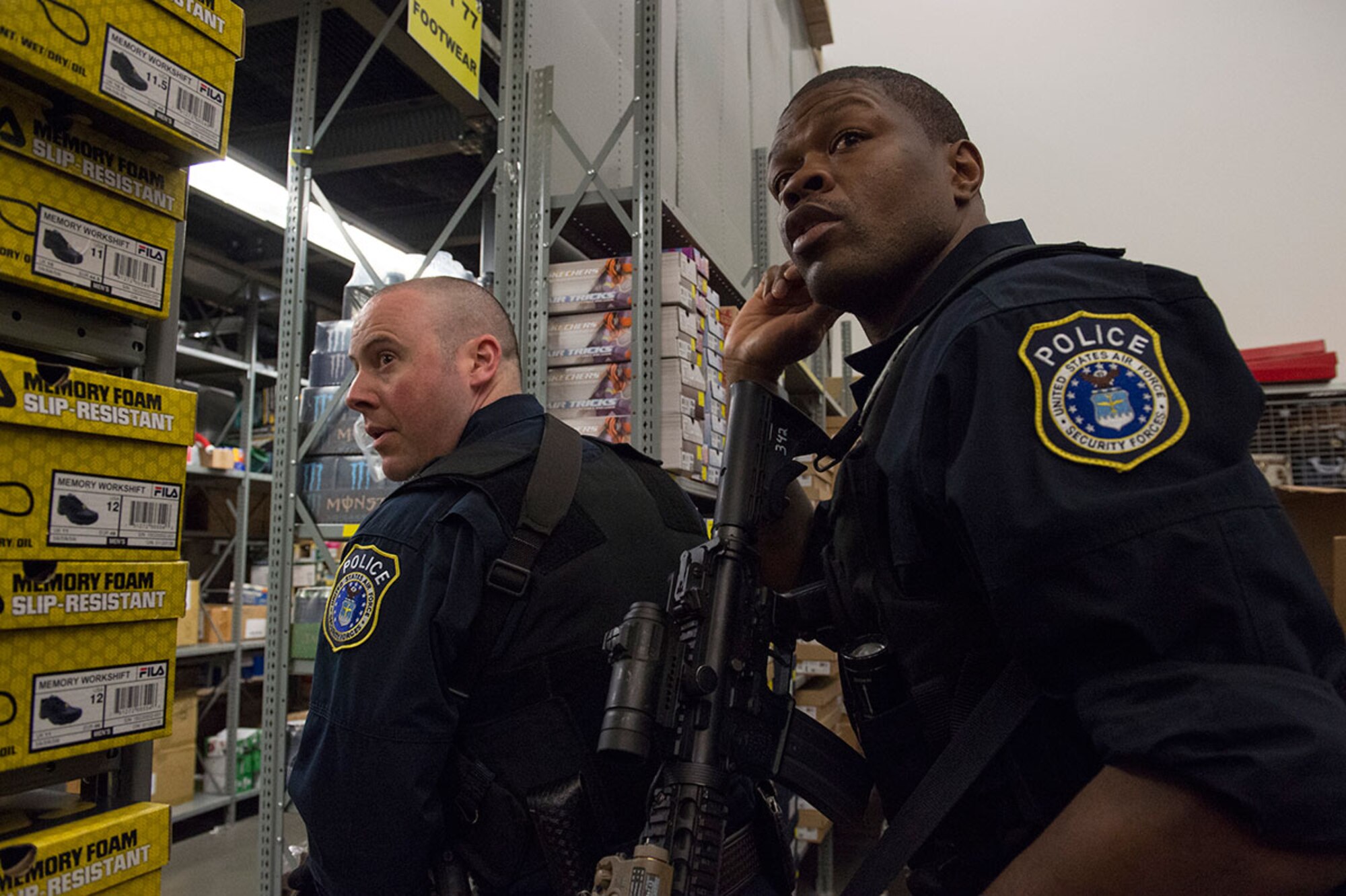 Joint Base Elmendorf-Richardson police officers, Brian Cannon, left, and Kevin Bullock, assigned to the 673rd Security Forces Squadron communicate with fellow officers while conducting high risk response training at the base exchange on JBER, Alaska, May 15, 2015. Pacific Air Forces High Risk Response Training is a project that provides security forces personnel with an intensive course based in real-life scenarios emphasizing effective tactics to eliminate active shooters and other threats. (U.S. Air Force photo/Alejandro Pena)
