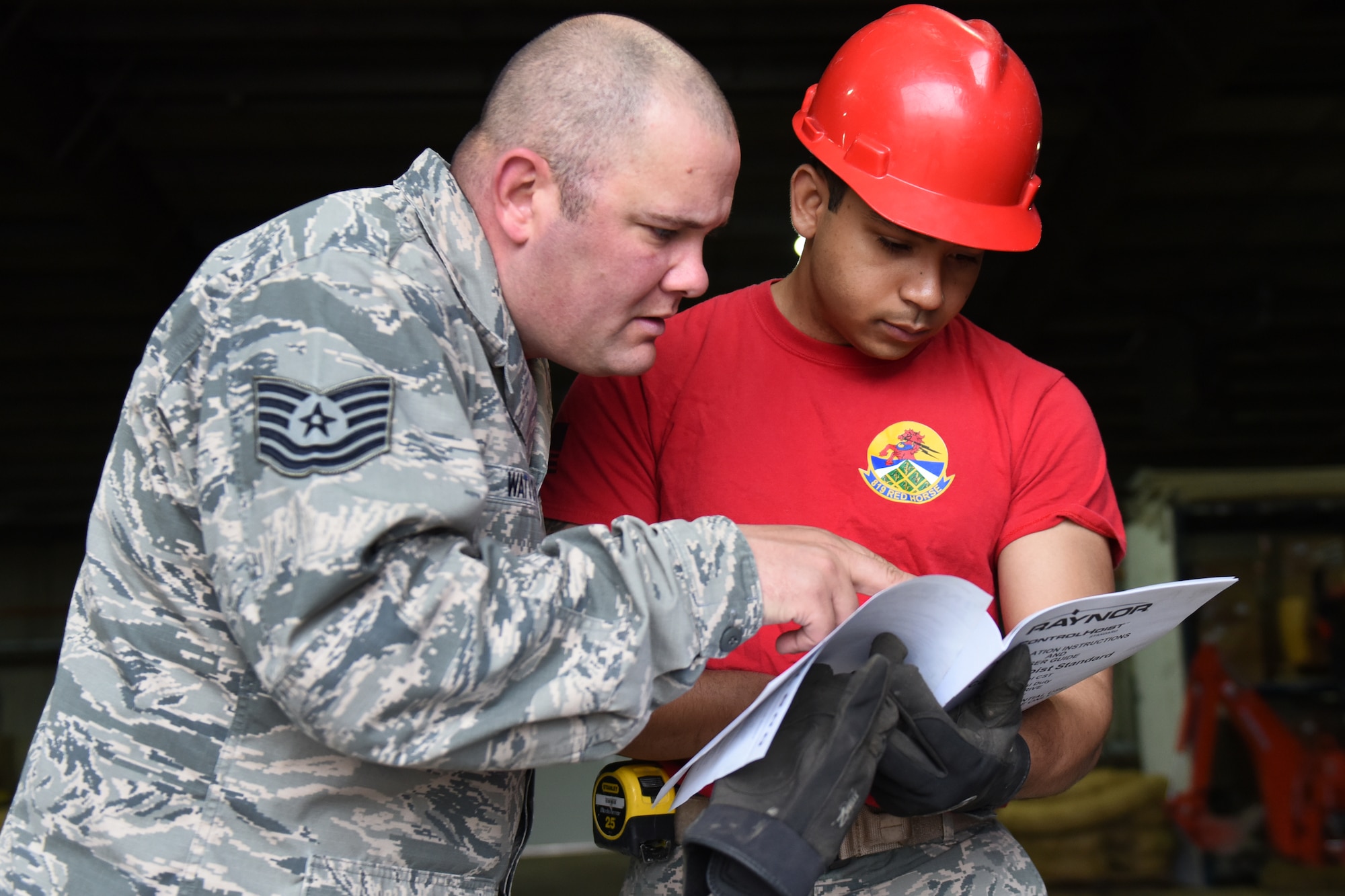 Tech. Sgt. Justin Watson, left, and Senior Airman Trevor Sanchez, 819th RED HORSE Squadron structures shop, review overhead door installation procedures May 20, 2015, at Malmstrom Air Force Base, Mont. The primary RED HORSE tasking in peacetime is to train for contingency and wartime operations. (U.S. Air Force photo/Chris Willis)