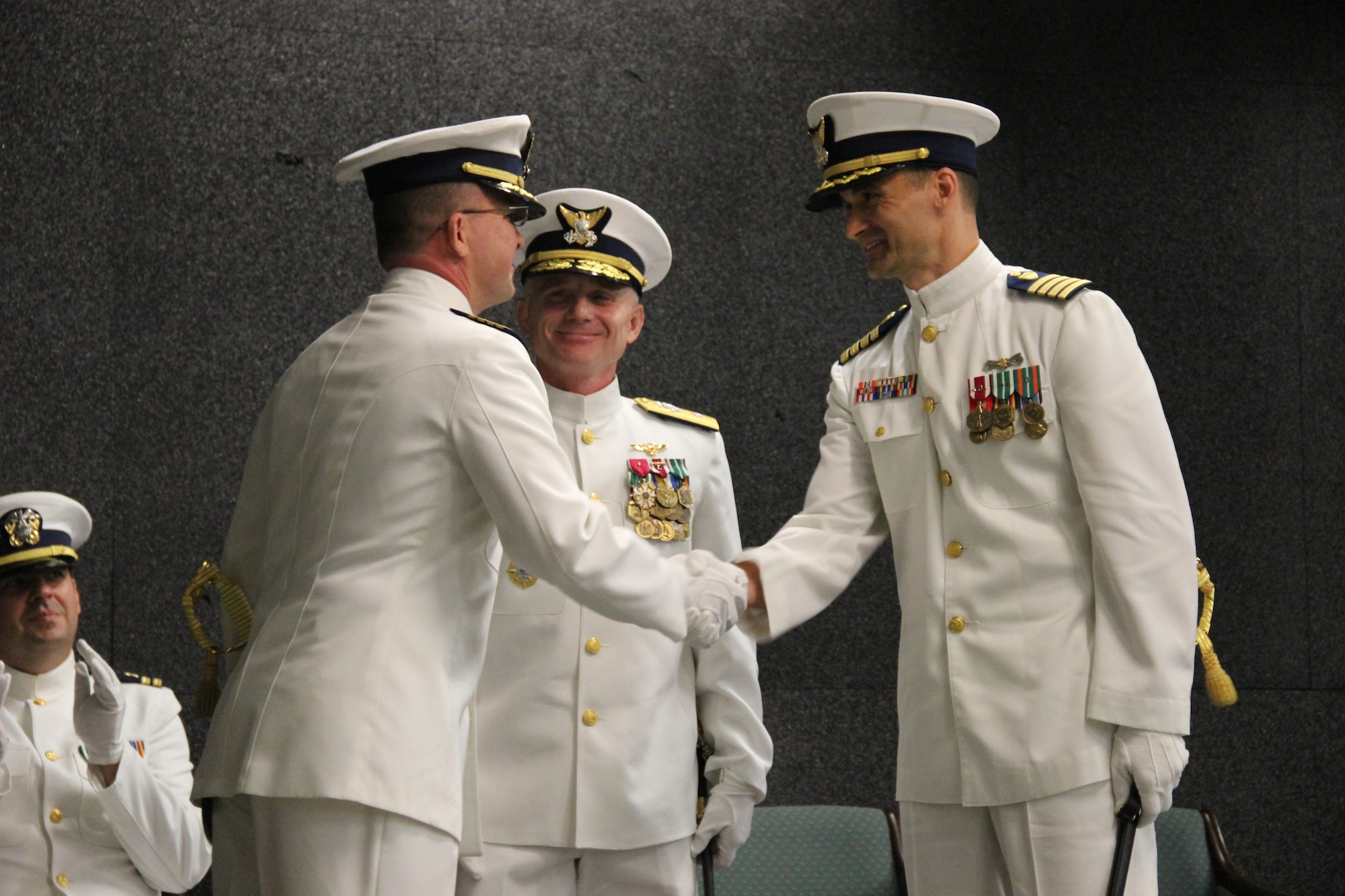 Captain Tom Walsh, Jr. (left) shakes hands with Captain Tim Haws (right) after effecting the relief during the Coast Guard Maritime Law Enforcement Academy's change of command ceremony May 12, 2015 in Charleston, S.C. The ceremony was presided over by Rear Admiral David Throop, commander of the Coast Guard Force Readiness Command located in Norfolk, Va. Captain Walsh departs for duty as chief, Training Division, Coast Guard Force Readiness Command and Captain Haws is reporting in from Coast Guard Training Center in Yorktown, Va. (Courtesy photo)

