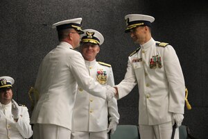 Captain Tom Walsh, Jr. (left) shakes hands with Captain Tim Haws (right) after effecting the relief during the Coast Guard Maritime Law Enforcement Academy's change of command ceremony May 12, 2015 in Charleston, S.C. The ceremony was presided over by Rear Admiral David Throop, commander of the Coast Guard Force Readiness Command located in Norfolk, Va. Captain Walsh departs for duty as chief, Training Division, Coast Guard Force Readiness Command and Captain Haws is reporting in from Coast Guard Training Center in Yorktown, Va. (Courtesy photo)
