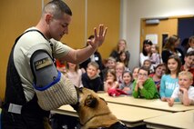 U.S. Air Force Staff Sgt. Joseph Serrano, 100th Security Forces Squadron Military Working Dog trainer from San Fernando, Calif., demonstrates the power and obedience of MWD Tomi at a Hearts Apart event May 20, 2015, on RAF Mildenhall, England. Hearts Apart is held monthly for all families of deployed Airmen and is hosted but units to show appreciation for the families and offer support during the Airmen’s absence. (U.S. Air Force photo by Senior Airman Christine Halan/Released)