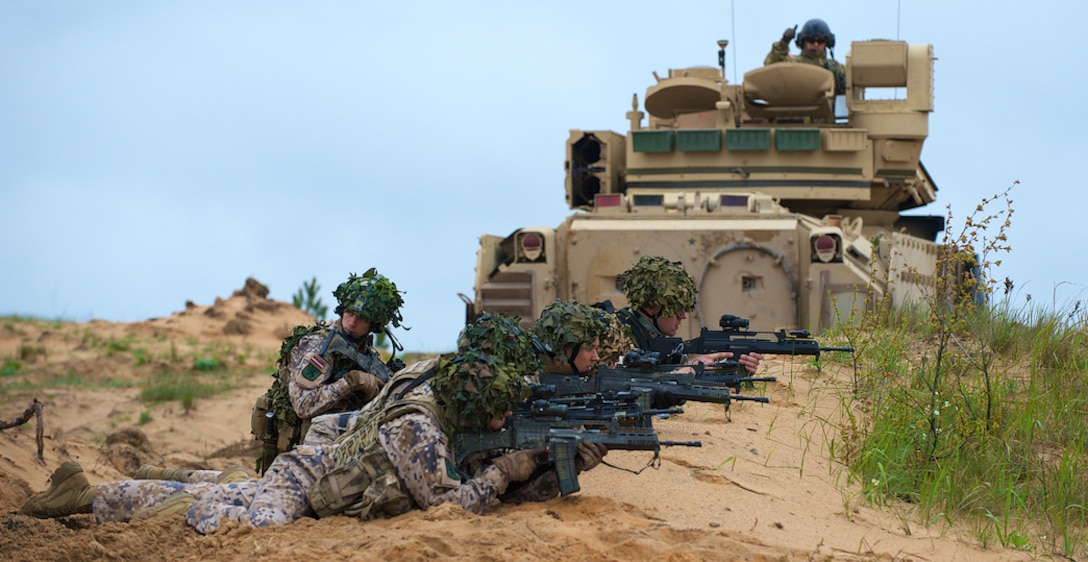 An M2 Bradley Fighting Vehicle crewman part of Company B, 2nd Battalion, 7th Infantry Regiment, 1st Armored Brigade Combat Team, 3rd Infantry Division out of Fort Stewart, Ga., signals for movement to soldiers from the 1st Infantry Battalion, Latvian Land Forces Infantry Brigade during joint gunnery training in Adazi, Latvia, May 21, 2015. U.S. soldiers assigned to the 173rd Airborne Brigade and 2nd Battalion, 7th Infantry Regiment, 1st Armored Brigade Combat Team, 3rd Infantry Division are currently deployed throughout Europe as part of Operation Atlantic Resolve, an ongoing, multinational partnership focused on joint training and security cooperation between the U.S. and other NATO allies. 