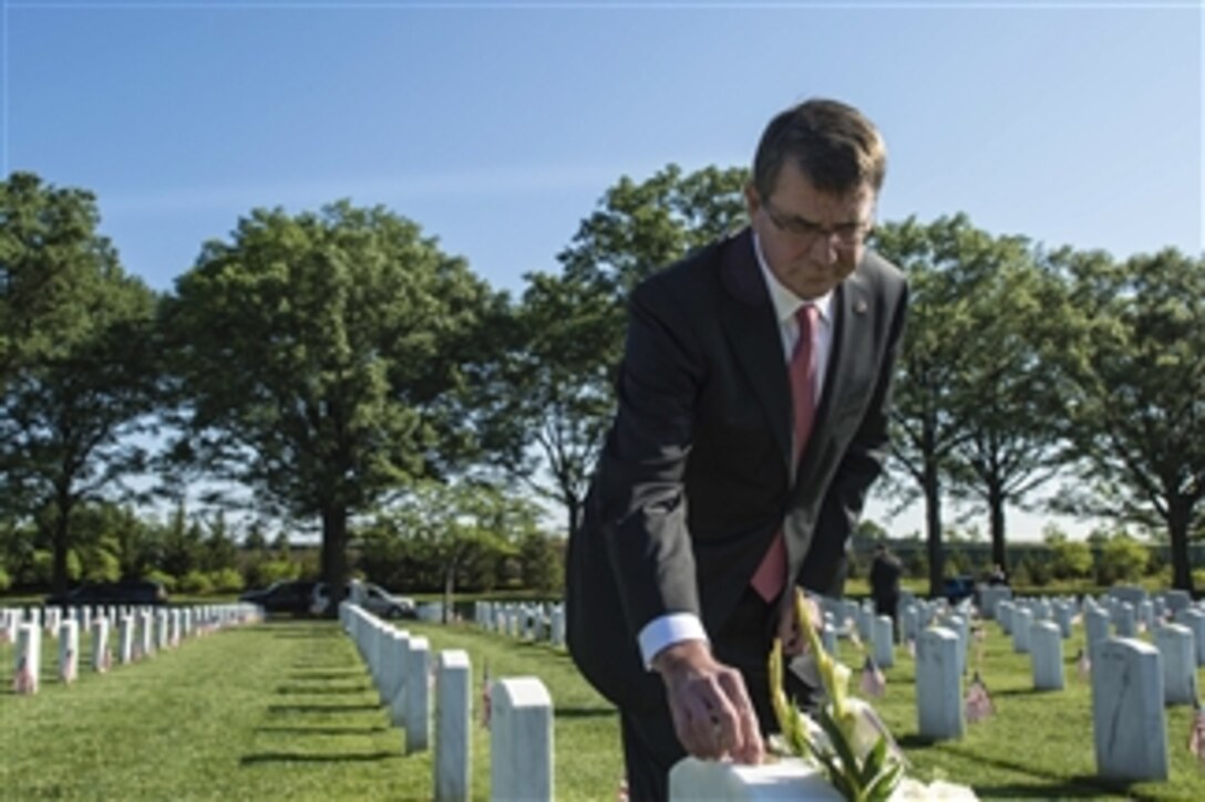 Defense Secretary Ash Carter leaves a challenge coin at the gravesite of Army Spc. Christopher David Horton at Arlington National Cemetery in Arlington, Va., May 22, 2015. Carter and his family members are friends with Horton's mother. Cemetery visitors often leave small rocks or personal markers on graves to let family members know they visited their loved ones. 