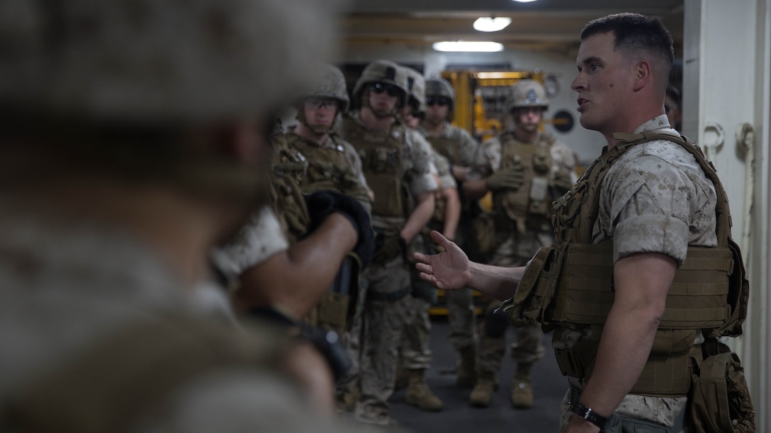 Sergeant Matthew Sanford, a squad leader of 2nd Platoon, Charlie Company, 1st Battalion, 6th Marines Regiment, instructs his Marines before practicing insertion and extraction drills aboard the USS San Antonio LPD May 19, 2015. The company will be participating in Fleet Week New York, New York to showcase what Marines and joint services have to offer in defense support. 