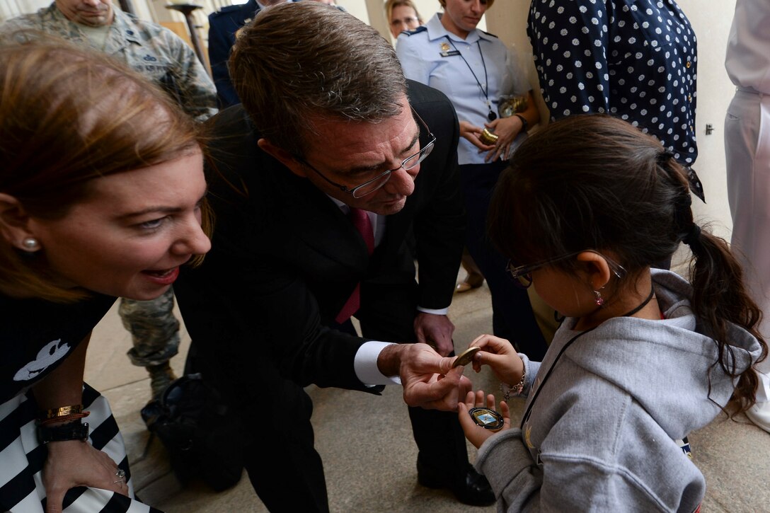 Defense Secretary Ash Carter presents a challenge coin to a child from the Tragedy Assistance Program for Survivors at the Pentagon, May 22, 2015.