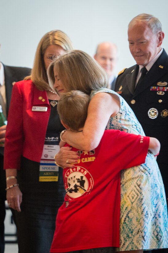 Deanie Dempsey, wife of Army Gen. Martin E. Dempsey, chairman of the Joint Chiefs of Staff, hugs a child as the chairman looks on during the 21st annual TAPS National Military Survivor Seminar and Good Grief Camp for Young Survivors in Arlington, Va., May 22, 2015.
