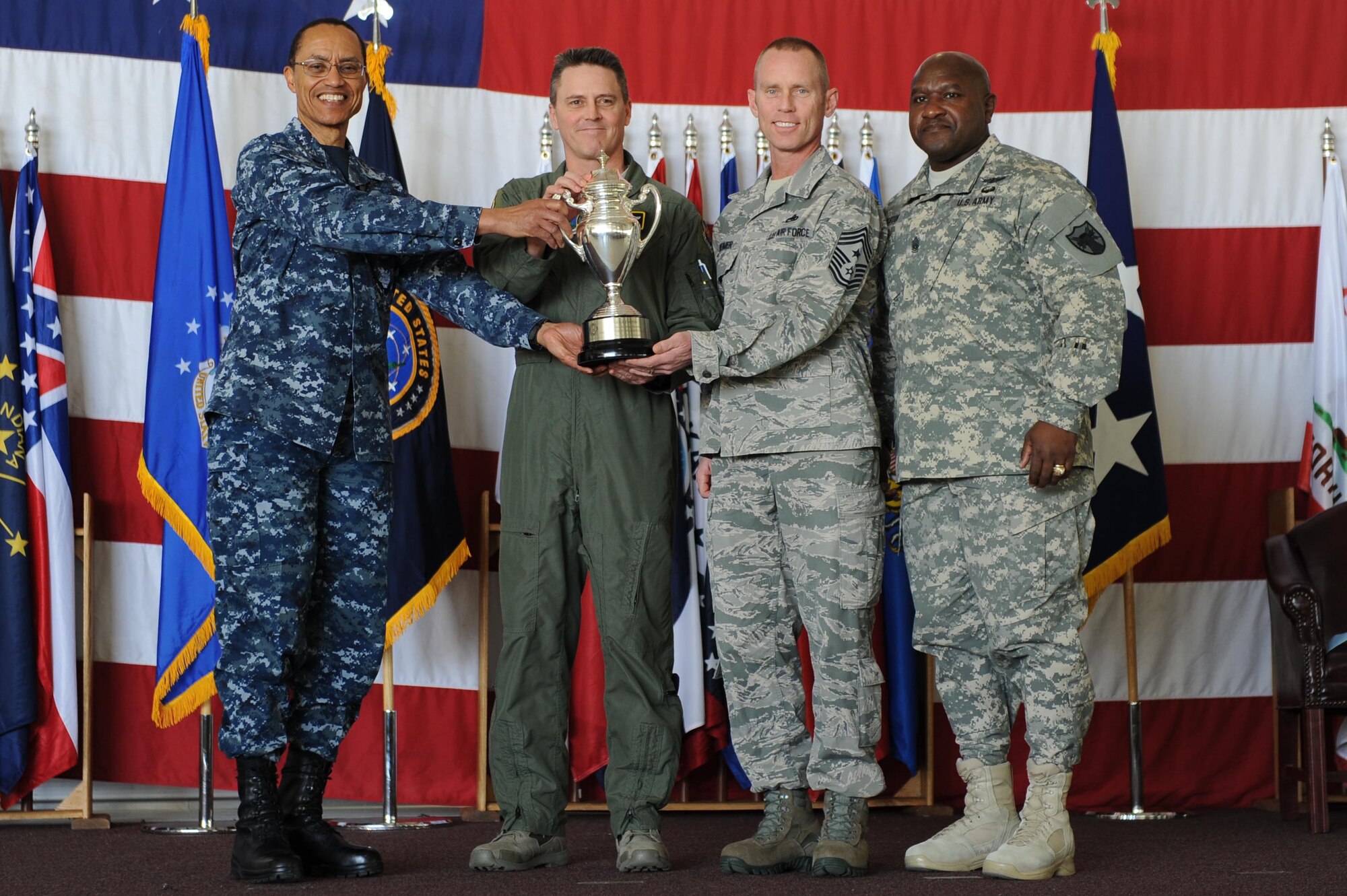 U.S. Navy Adm. Cecil D. Haney (left), U.S. Strategic Command commander, and U.S. Army Command Sgt. Maj. Patrick Z. Alston (right), USSTRATCOM senior enlisted leader, present the 2014 Omaha Trophy, strategic aircraft operations category, to U.S. Air Force Col. Jason Armagost (center left), 5th Bomb Wing commander, and U.S. Air Force Chief Master Sgt. Geoff Weimer, 5th Bomb Wing command chief, on Minot Air Force Base, N.D., May 20, 2015. The unit is one of four Omaha Trophy-winning units for 2014 and joins winners in the intercontinental ballistic missile wing, ballistic missile submarine and global operations (space/cyberspace) unit categories. Those receiving the awards represent units throughout USSTRATCOM which are critical to fulfilling the combatant command's primary mission: to detect, deter and prevent strategic attacks against the United States and its allies. USSTRATCOM is one of nine unified commands under the Department of Defense and is responsible for strategic deterrence; space operations; cyberspace operations; joint electronic warfare; global strike; missile defense; intelligence, surveillance and reconnaissance; combating weapons of mass destruction; and analysis and targeting. (U.S. Air Force photo/Senior Airman Kristoffer Kaubisch)