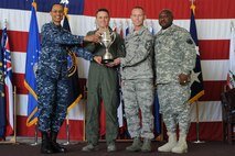 U.S. Navy Adm. Cecil D. Haney (left), U.S. Strategic Command commander, and U.S. Army Command Sgt. Maj. Patrick Z. Alston (right), USSTRATCOM senior enlisted leader, present the 2014 Omaha Trophy, strategic aircraft operations category, to U.S. Air Force Col. Jason Armagost (center left), 5th Bomb Wing commander, and U.S. Air Force Chief Master Sgt. Geoff Weimer, 5th Bomb Wing command chief, on Minot Air Force Base, N.D., May 20, 2015. The unit is one of four Omaha Trophy-winning units for 2014 and joins winners in the intercontinental ballistic missile wing, ballistic missile submarine and global operations (space/cyberspace) unit categories. Those receiving the awards represent units throughout USSTRATCOM which are critical to fulfilling the combatant command's primary mission: to detect, deter and prevent strategic attacks against the United States and its allies. USSTRATCOM is one of nine unified commands under the Department of Defense and is responsible for strategic deterrence; space operations; cyberspace operations; joint electronic warfare; global strike; missile defense; intelligence, surveillance and reconnaissance; combating weapons of mass destruction; and analysis and targeting. (U.S. Air Force photo/Senior Airman Kristoffer Kaubisch)