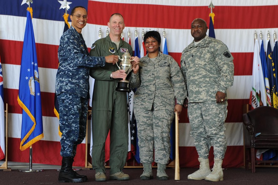 U.S. Navy Adm. Cecil D. Haney (left), U.S. Strategic Command commander, and U.S. Army Command Sgt. Maj. Patrick Z. Alston (right), USSTRATCOM senior enlisted leader, present the 2014 Omaha Trophy, intercontinental ballistic missile wing category, to U.S. Air Force Col. Michael Lutton (center left), 91st Missile Wing commander, and U.S. Air Force Chief Master Sgt. Felica Noil, 91st Missile Wing command chief, on Minot Air Force Base, N.D., May 20, 2015. The unit is one of four Omaha Trophy-winning units for 2014 and joins winners in the strategic aircraft operations wing, ballistic missile submarine and global operations (space/cyberspace) unit categories. Those receiving the awards represent units throughout USSTRATCOM which are critical to fulfilling the combatant command's primary mission: to detect, deter and prevent strategic attacks against the United States and its allies. USSTRATCOM is one of nine unified commands under the Department of Defense and is responsible for strategic deterrence; space operations; cyberspace operations; joint electronic warfare; global strike; missile defense; intelligence, surveillance and reconnaissance; combating weapons of mass destruction; and analysis and targeting. (U.S. Air Force photo/Senior Airman Kristoffer Kaubisch)