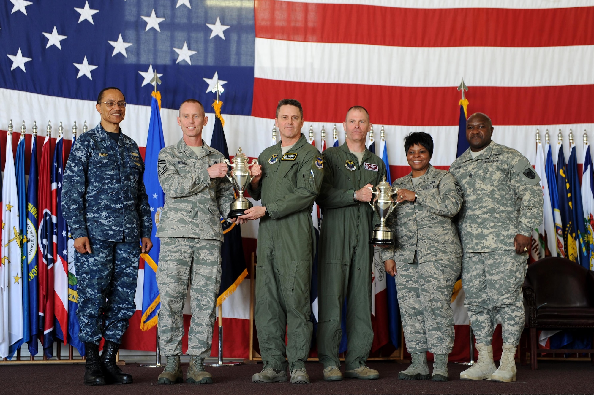 U.S. Navy Adm. Cecil D. Haney (left), U.S. Strategic Command commander, and U.S. Army Command Sgt. Maj. Patrick Z. Alston (right), USSTRATCOM senior enlisted leader, present 2014 Omaha Trophies, strategic aircraft operations and intercontinental ballistic missile wing categories, to the 5th Bomb Wing and 91st Missile Wing respectively, on Minot Air Force Base, N.D., May 20, 2015. U.S. Air Force Col. Jason Armagost (center left), 5th Bomb Wing commander; U.S. Air Force Chief Master Sgt. Geoff Weimer (second from left), 5th Bomb Wing command chief; U.S. Air Force Col. Michael Lutton (center right), 91st Missile Wing commander, and U.S. Air Force Chief Master Sgt. Felica Noil, 91st Missile Wing command chief, accepted the trophies on behalf of their units. Minot is home to two of the four Omaha Trophy-winning units for 2014, which joined winners in the ballistic missile submarine and global operations (space/cyberspace) unit categories. Those receiving the awards represent units throughout USSTRATCOM which are critical to fulfilling the combatant command's primary mission: to detect, deter and prevent strategic attacks against the United States and its allies. USSTRATCOM is one of nine unified commands under the Department of Defense and is responsible for strategic deterrence; space operations; cyberspace operations; joint electronic warfare; global strike; missile defense; intelligence, surveillance and reconnaissance; combating weapons of mass destruction; and analysis and targeting. (U.S. Air Force photo/Senior Airman Kristoffer Kaubisch)