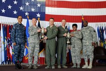 U.S. Navy Adm. Cecil D. Haney (left), U.S. Strategic Command commander, and U.S. Army Command Sgt. Maj. Patrick Z. Alston (right), USSTRATCOM senior enlisted leader, present 2014 Omaha Trophies, strategic aircraft operations and intercontinental ballistic missile wing categories, to the 5th Bomb Wing and 91st Missile Wing respectively, on Minot Air Force Base, N.D., May 20, 2015. U.S. Air Force Col. Jason Armagost (center left), 5th Bomb Wing commander; U.S. Air Force Chief Master Sgt. Geoff Weimer (second from left), 5th Bomb Wing command chief; U.S. Air Force Col. Michael Lutton (center right), 91st Missile Wing commander, and U.S. Air Force Chief Master Sgt. Felica Noil, 91st Missile Wing command chief, accepted the trophies on behalf of their units. Minot is home to two of the four Omaha Trophy-winning units for 2014, which joined winners in the ballistic missile submarine and global operations (space/cyberspace) unit categories. Those receiving the awards represent units throughout USSTRATCOM which are critical to fulfilling the combatant command's primary mission: to detect, deter and prevent strategic attacks against the United States and its allies. USSTRATCOM is one of nine unified commands under the Department of Defense and is responsible for strategic deterrence; space operations; cyberspace operations; joint electronic warfare; global strike; missile defense; intelligence, surveillance and reconnaissance; combating weapons of mass destruction; and analysis and targeting. (U.S. Air Force photo/Senior Airman Kristoffer Kaubisch)