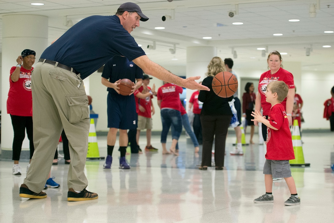 Former NBA player Gheorghe Muresan tosses a basketball to a child with the Tragedy Assistance Program for Survivors at the Pentagon, May 22, 2015. 