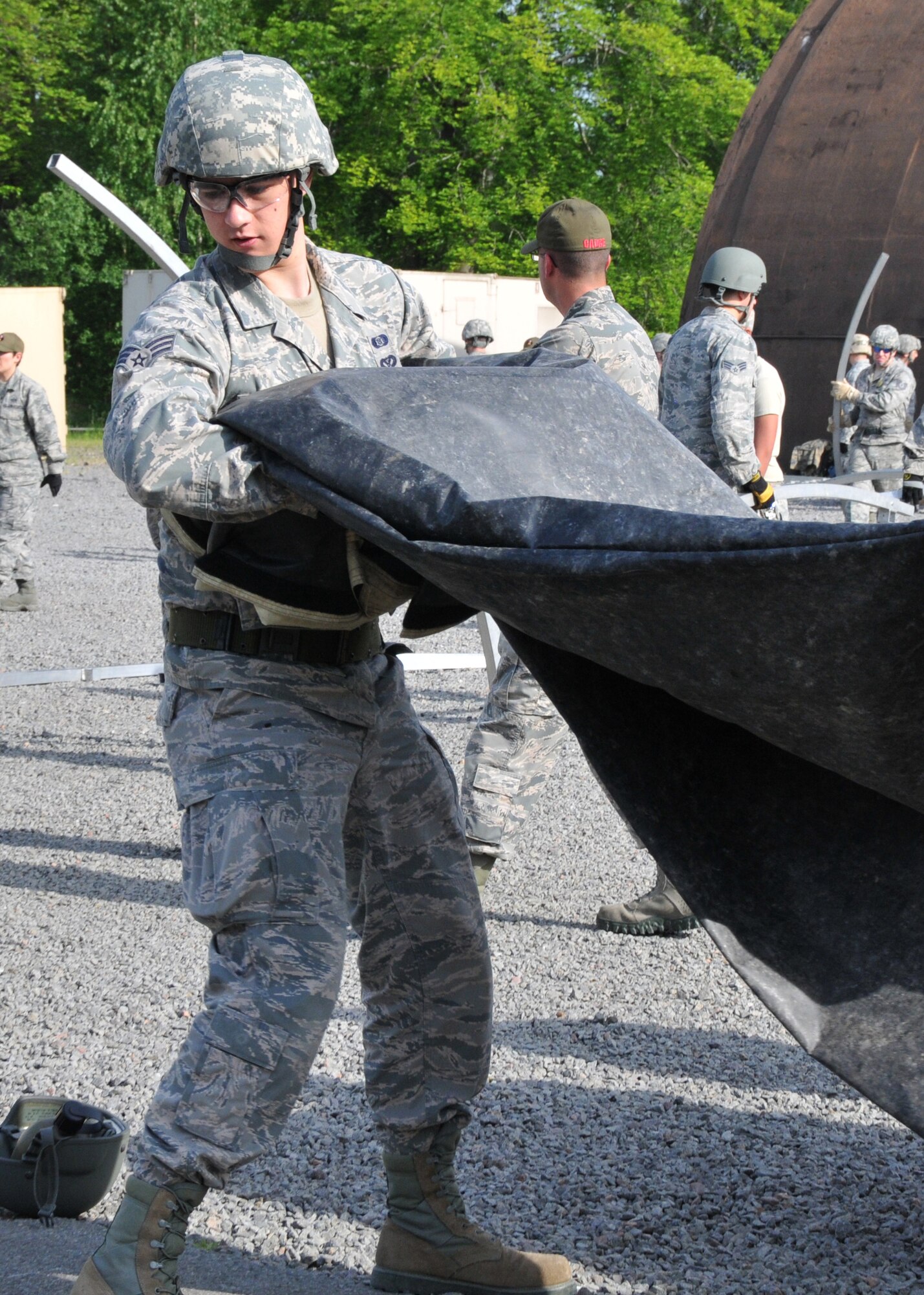 An Airman from the 104th Emergency Management Flight, Barnes Air National Guard Base, Westfield, Mass., carries a fly cover for a Triple-S tent, May 12, 2015, Ramstein Air Base, Germany. He is building a tent with other active duty, guard and reserve members in preparation for Exercise Silver Flag. (U.S. Air National Guard photo by Tech. Sgt. Melanie J. Casineau/Released)