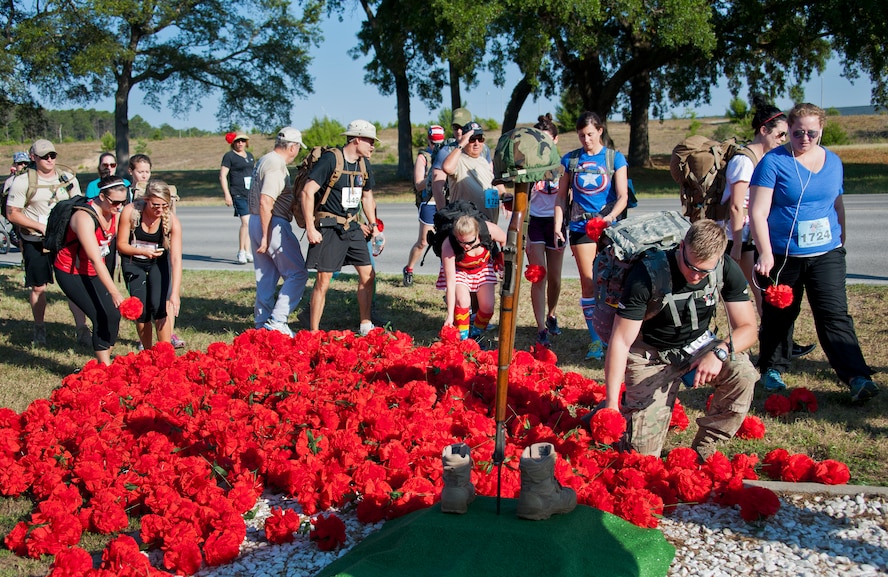 Runners and ruck marchers pay their respects at the All Wars Memorial during the 30th Anniversary Memorial Gate to Gate run May 23 at Eglin Air Force Base, Fla.  Runners and walkers dropped off carnations in front of the All Wars Memorial as they passed by on the race route.  More than 1,500 participated in this year’s event.  (U.S. Air Force photo/Samuel King Jr.)
