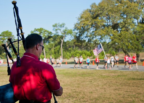 Senior Master Sgt. Steve Bicknell, 919th Special Operations Wing, plays the bagpipes as runners and walkers move toward the All Wars Memorial during the 30th Anniversary Memorial Gate to Gate run May 23 at Eglin Air Force Base, Fla.  Runners and walkers dropped off carnations in front of the All Wars Memorial as they passed by on the race route.  More than 1,500 participated in this year’s event.  (U.S. Air Force photo/Samuel King Jr.)